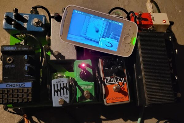 photograph of a pedalboard with a baby monitor on it