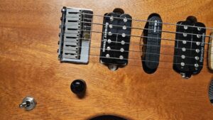 horizontal photograph of RF40 custom partscaster's bridge, pickups, volume knob, and pickup selector switch